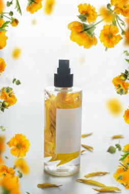 Doğal parfüm ya da beyaz arka planda sarı çiçekli gerekli yağ spreyi şişesi..