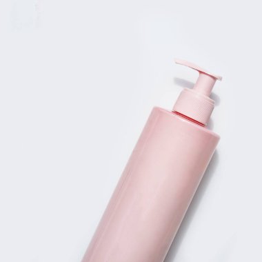 Beyaz arka planda pompaları olan pembe güzellik ürünü şişesi.