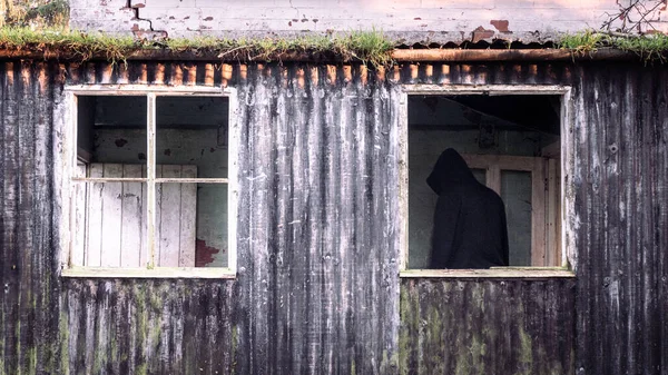 Przerażająca Postać Kapturze Powrotem Kamery Opuszczonym Budynku Oprawione Przez Okno — Zdjęcie stockowe