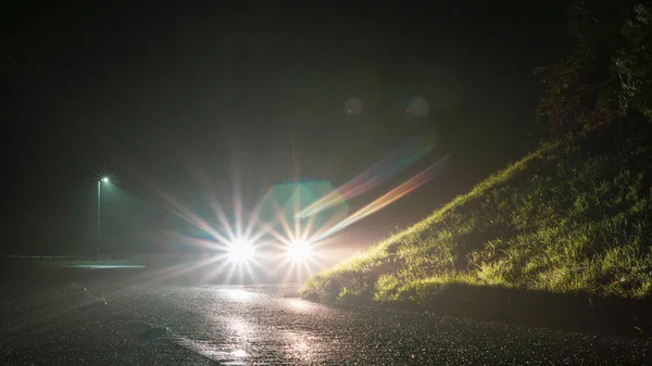 Autoscheinwerfer Leuchten Nachts Auf Einer Gespenstisch Nebelverhangenen Leeren Landstraße Stockfoto