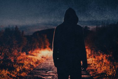 Esrarengiz, ürkütücü bir figür, gecenin bir yarısı ürkütücü bir köy yolunda ışık saçıyor. Bir grunge, taneli vintage düzenleme ile.
