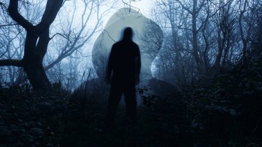 Tüyler ürpertici bir kış gününde ormanda dikilen tüyler ürpertici bir korku figürüyle kapüşonlu bir figürün çift pozu..