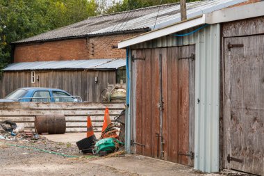 Terk edilmiş endüstriyel ekipman ve hafif sanayi binalarının dışında bir araba.