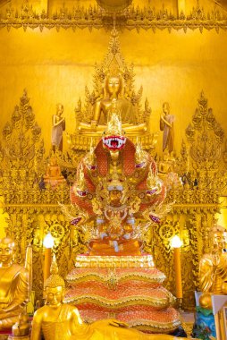  Wat Pak Nam Jolo 'nun ana mabedi, karmaşık oymalar ve süslemelerle çevrili bir naga tahtında oturan çarpıcı bir altın Buda' ya ev sahipliği yapar..