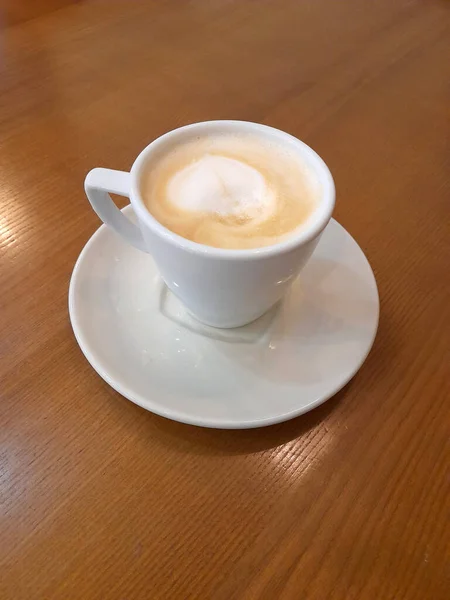 Coffee in a white cup. White cup with coffee on a wooden surface