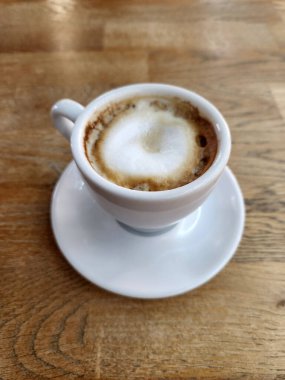 Beyaz fincanda demlenmiş kahve. Tahta bir masanın üzerinde kahve olan beyaz bir fincan.