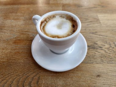 Beyaz fincanda demlenmiş kahve. Tahta bir masanın üzerinde kahve olan beyaz bir fincan.