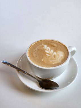 Beyaz bir masada beyaz bir fincanda kahve. Kadeh ve kaşık