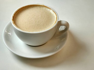 Beyaz bir masanın üzerinde kahve olan beyaz bir fincan. Beyaz bardakta kahve.