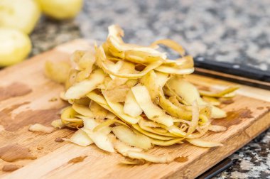 Patates, bir evin mutfağında yatay bir ahşabın üzerinde soyuluyor. Geleneksel İspanyol omleti hazırlama kavramı.