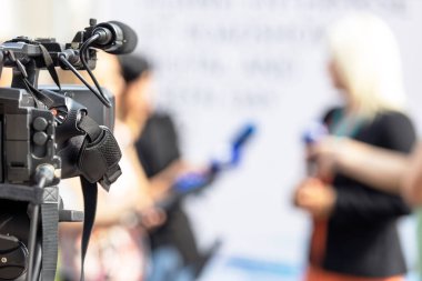 Odaklı video kamera, basın konferansında bulanık haberler mikrofonlar tutarak kadın siyasetçi veya iş kadınıyla medya röportajı yapıyor