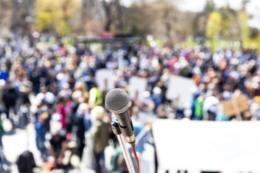 Protesto ya da halk gösterileri, mikrofona odaklanma, arka planda bulanık insan kalabalığı
