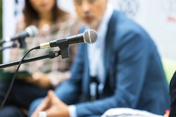 stock image Microphone in focus at round table event or business conference. Public speaking concept.