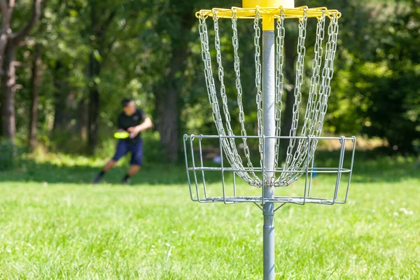 公園で空飛ぶ円盤を投げディスクゴルフ選手 フォーカスのチェーンバスケット — ストック写真
