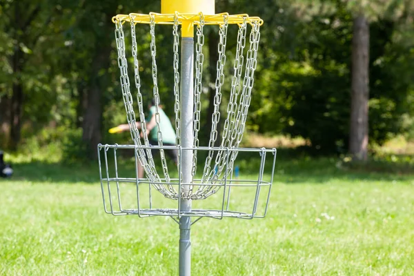 公園で空飛ぶ円盤を投げディスクゴルフ選手 フォーカスのチェーンバスケット — ストック写真