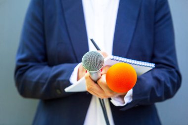 Basın konferansında ya da medya etkinliğinde kadın gazeteci, notlar yazma, mikrofon tutma