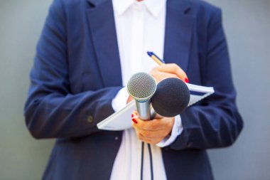 Basın konferansında ya da medya etkinliğinde kadın gazeteci, notlar yazma, mikrofon tutma