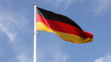 Mavi gökyüzüne doğru dalgalanan Alman bayrağı