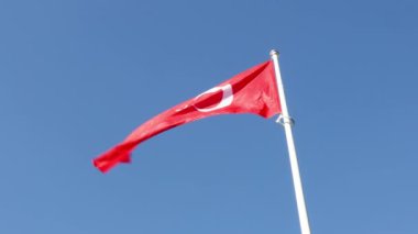 Mavi gökyüzüne karşı rüzgarda dalgalanan Türkiye bayrağı. Yavaş çekim videosu.