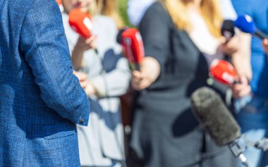 Basın toplantısında ellerinde mikrofon tutan bir grup gazeteci ve TV muhabiri