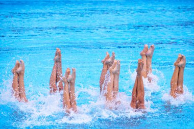 Senkronize yüzme takımı yüzme havuzunda sanatsal yüzme yapıyor.