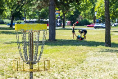 Halk parkında uçan disk golf oyunu oynayan insanlar.