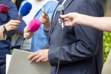 Basın konferansında veya medya etkinliğinde ellerinde mikrofon bulunan bir grup gazeteci ve gazeteci