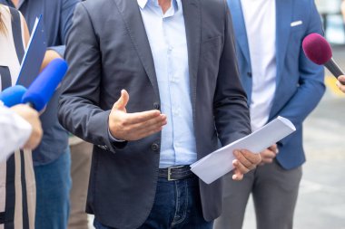 Kadın muhbir elinde gizli belge tutarken basın toplantısı veya haber etkinliğinde gazetecilere açıklama yapıyor