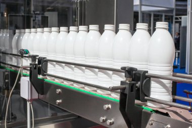 Modern bir üretim tesisinde endüstriyel taşıma bandındaki plastik şişeler.