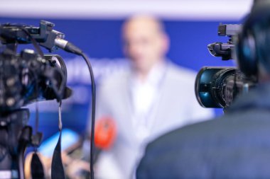 TV kameraları önünde basın toplantısı ya da medya röportajı yapan bulanık bir konuşmacı