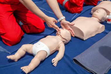 İlk yardım eğitimi öğretmenlerin bebek ve yetişkin suni teneffüs teknikleri uyguladığını gösteriyor.