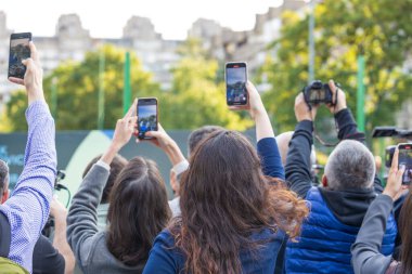 Açık hava etkinliğini yakalamak için akıllı telefonlar ve kameralar kullanan bir kalabalık.