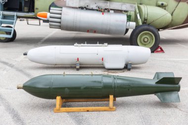 Military aviation weapons display featuring aerial unguided dumb bomb, rocket pods, and guided missile systems mounted on aircraft at air force base exhibition event