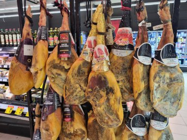 Geleneksel İspanyol et yemeğinden bir sürü tütsülenmiş bacak - markette sallanan jambon. BARCELONA, İSPAN - 16 Kasım 2022: