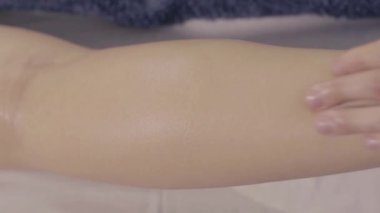 Genç bir kadın, vücut rahatlığı ve cilt bakımı için lüks bir spa salonunda erkek masörle bacak masajı yaptırıyor. Yavaş çekim, yakın çekim..