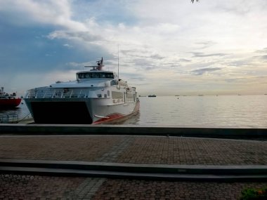 Ferry in port, with calm sea behind clipart