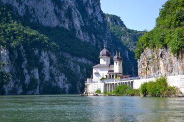 Mraconia Manastırı, Tuna Nehri boyunca uzanan ormanlık uçurumların arasına kuruludur. Kubbeli kuleler ve Demir Kapılar 'ın doğal güzellikleriyle çevrilidir..