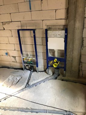 İnşaat sahasında beton blok duvar, tesisat bağlantıları ve görülebilir kabloyla tamamlanmamış bir zemin yer alıyor..