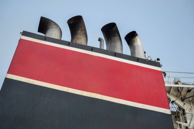 The image shows the red and black smokestacks of a ship with a white stripe, set against a clear blue sky, highlighting the vessel's industrial design. clipart