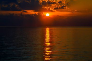 Engin okyanusun üzerinde yansıyan ışınlarla gün batımı