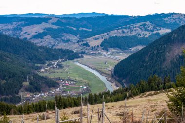 Dolambaçlı nehri olan sakin bir vadi, kemerli viyadük, yuvarlanan tepeler, sık ormanlar, dağınık evler, tarım arazileri ve ön planda kırsal ahşap bir çit..