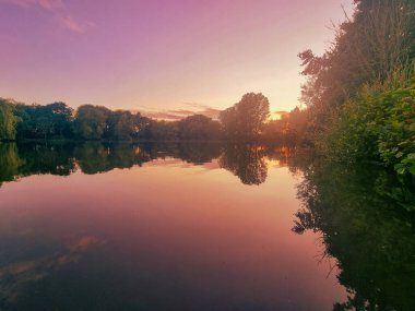 Arka planda güzel bir günbatımı olan sakin bir göl.