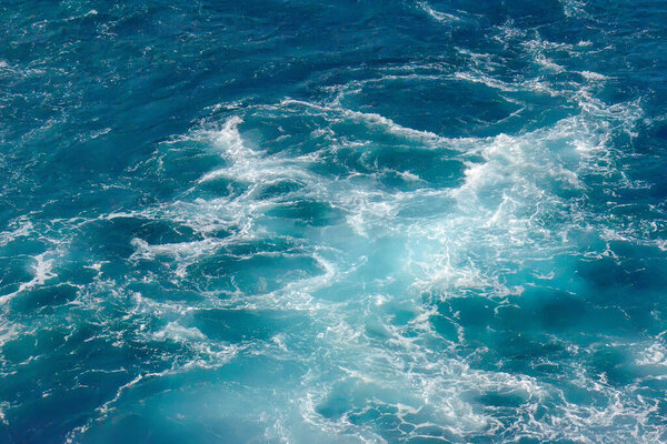 Набухание океанской воды с волнами и пеной, с глубокими синими и бирюзовыми тонами. Сцена подчеркивает естественное движение и текстуру.