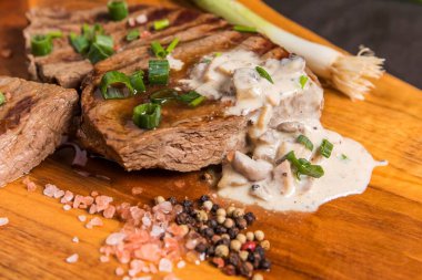 Ahşap bir tahtanın üzerinde mantar soslu biftek. Kaliteli sığır. Barbekü sezonu. Orta pişmiş biftek..