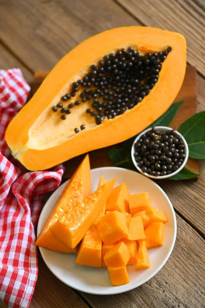 stock image papaya fruits on wooden backgroud, fresh ripe papaya slice on white plate tropical fruit with papaya seed and leaf leaves from papaya tree 