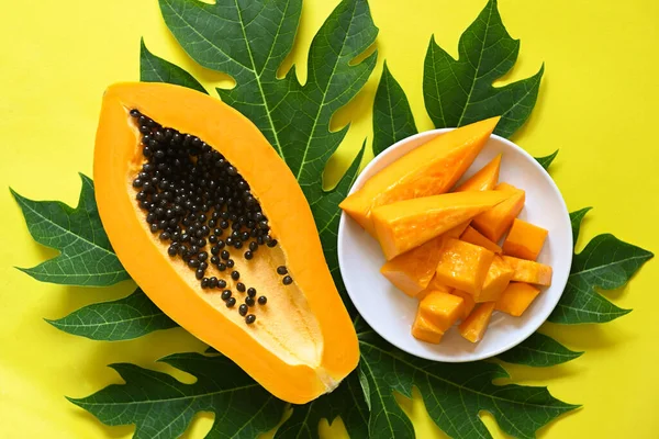 papaya fruits on yellow backgroud, fresh ripe papaya slice tropical fruit with papaya seed and leaf leaves from papaya tree - top view