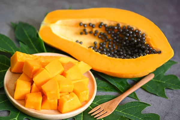 papaya fruits on dark backgroud, fresh ripe papaya slice cut in half tropical fruit with papaya seed and leaf leaves from papaya tree - top view