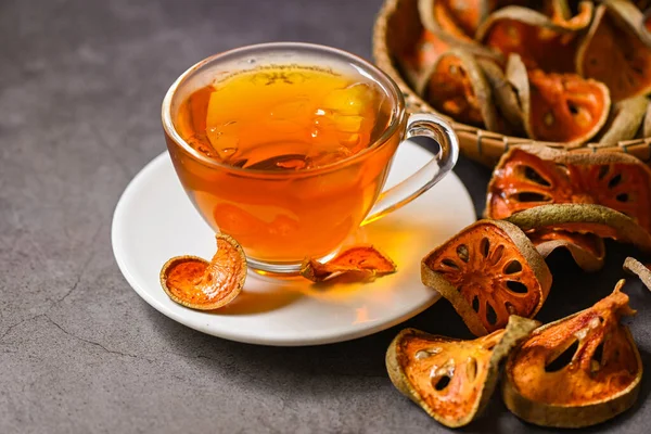 Bael tea on glass with dried bael slices on dark background, Bael  juice - Dry bael fruit tea for health - Aegle marmelos