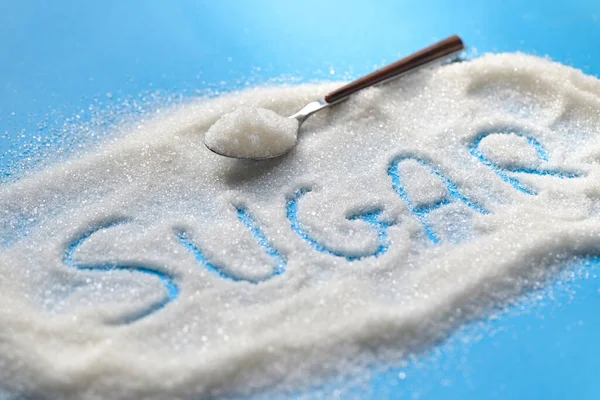 Sugar on spoon and blue background, white sugar for food and sweets dessert candy heap of sweet sugar crystalline granulated