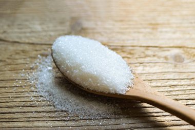 Kaşık ve ahşap zemin üzerinde şeker, yiyecek için beyaz şeker ve tatlı şeker yığını şeker kristalize granülü şeker.